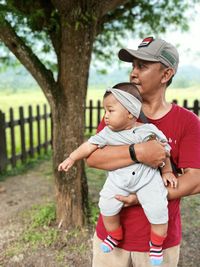 Friends standing against tree