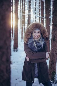 Portrait of smiling young woman standing in snow