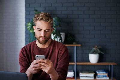 Young man using mobile phone while sitting at home