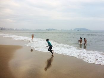 People playing on beach against sky