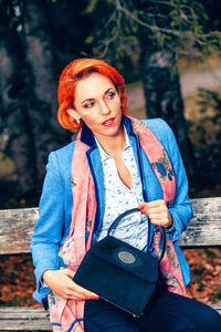 Woman holding purse while sitting on seat