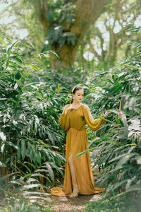 Portrait of young woman standing against plants