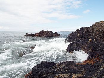 Rock formations on beach against sky