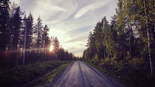 Empty road amidst trees against sky during sunset