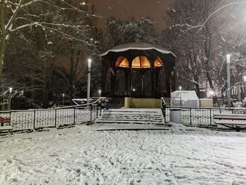 Bicycle on snow covered field by building at night