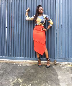 Full length portrait of young woman standing against gate