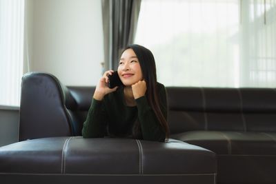 Portrait of young woman sitting on sofa at home