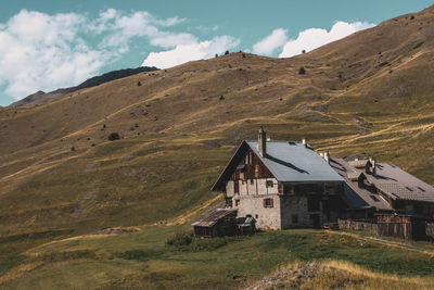 House on field by mountain against sky