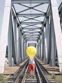 Low section of man holding balloon while standing on railroad track