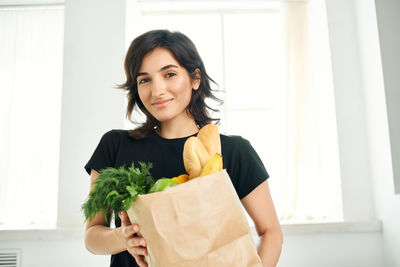 Portrait of smiling woman standing against wall