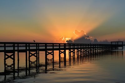 Silhouette pier over sea against sky during sunset