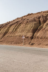 Rear view of person walking on road against clear sky