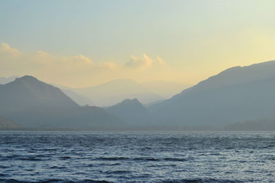 Scenic view of sea and mountains against sky during sunset