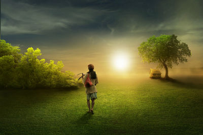 Farmer walking on field against sky during sunset