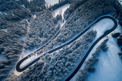 Aerial view of winding road amidst trees during winter