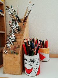 Colored pencils and paintbrushes in containers on table