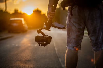 Man with umbrella standing in city during sunset