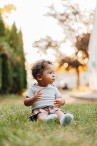 Smiling boy looking away while sitting at lawn