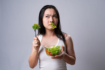 Portrait of woman eating food against white background