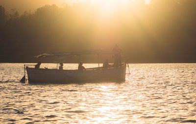 Men in boat sailing on river during sunset