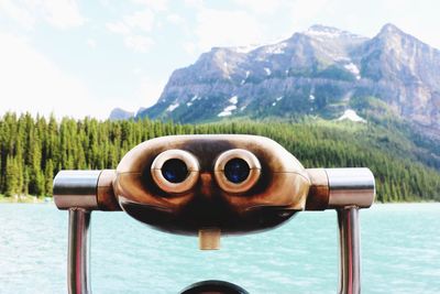 Close-up of coin-operated binoculars against mountain range