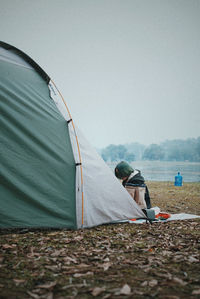 Men sitting on tent against sky