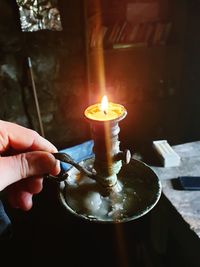 Close-up of hand holding lit candle