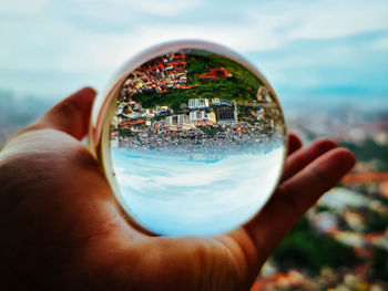 Close-up of person holding glass against sky