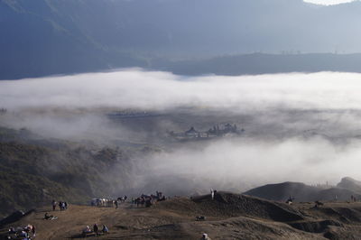 People on mountain against sky during foggy weather