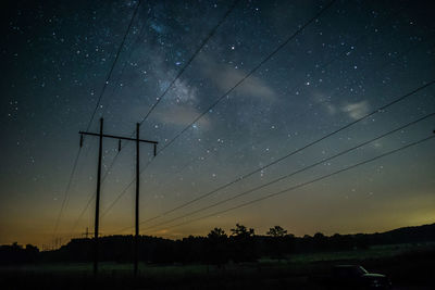 Low angle view of silhouette electricity pylon against sky at night