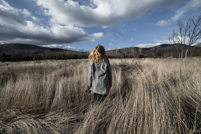 Rear view of woman standing on field against sky