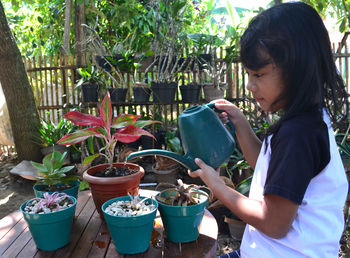 Girl watering potted plants at yard