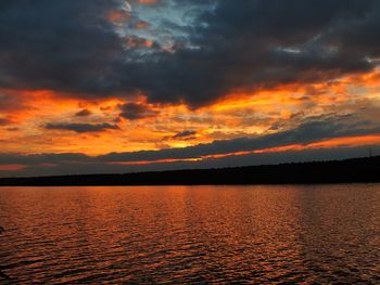 Scenic view of lake against dramatic sky during sunset