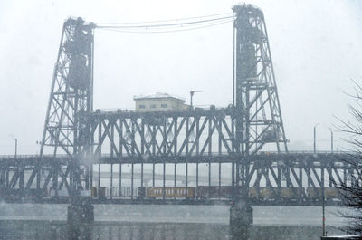 Bridge over river in city against sky