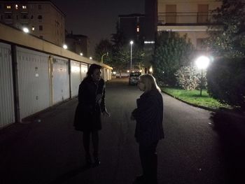 People walking on illuminated street at night