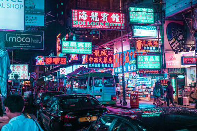 People on illuminated street in city at night