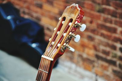 Cropped image of guitar against brick wall