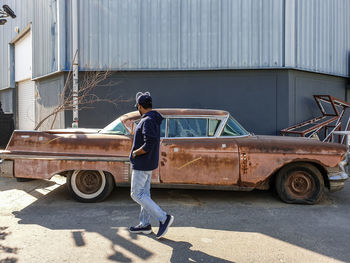 A young man walking by an old nostalgic car