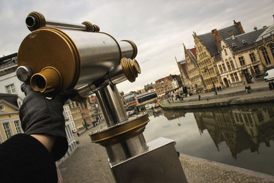 Cropped hand holding coin-operated binoculars in city