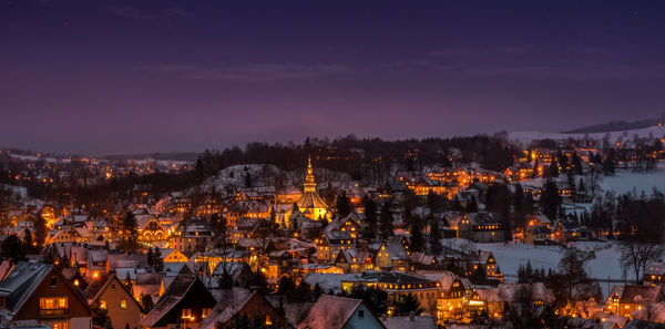 Illuminated cityscape against sky at night during winter