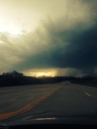 Cars on road against cloudy sky