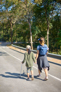 Rear view of two children on road against trees