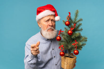 Midsection of woman holding christmas tree against blue background