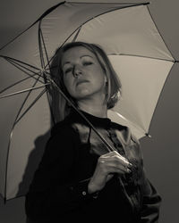 Portrait of woman under umbrella against gray background