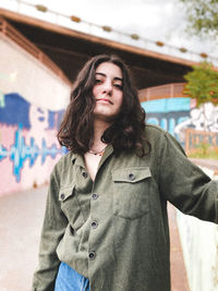 Portrait of beautiful young woman standing against graffiti