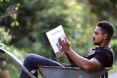 Side view of young man sitting on book