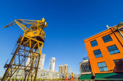 Crane at construction site in city against clear blue sky