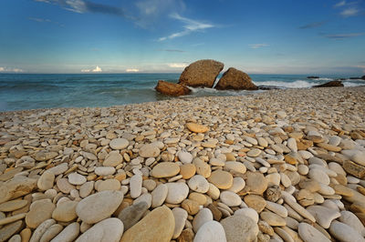 Rocks on shore at beach against sky
