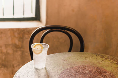 Glass of sparkling water with slice of lemon on table at home