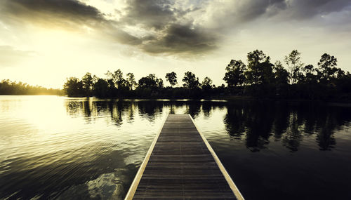 Pier over lake against sky during sunset